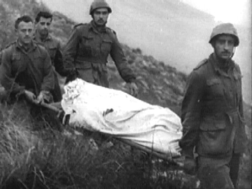 <p>Monte Lungo, dicembre 1943. Fanti italiani trasportano il corpo di un commilitone caduto. Le perdite dei combattimenti dell'8 e del 16 dicembre 1943, assommarono a 57 caduti e 112 feriti.</p><p class='eng'>Monte Lungo, December 1943. Italian infantrymen carrying the body of a fallen comrade. From the 8th to the 16th of December 1943, 57 soldiers were killed and 112 were wounded.</p>