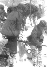 <p>Soldati tedeschi trasportano con fatica un pesante proiettile di artiglieria su per una montagna innevata.</p>