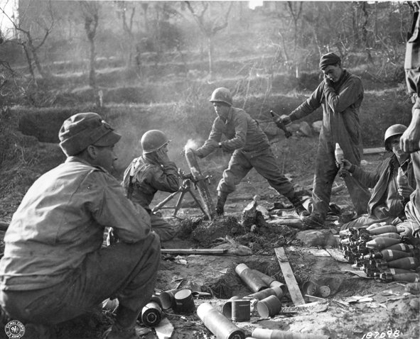 <p class='eng'>28 Jan 1944 – Fifth Army, Rapido River Area, Italy – MM-5-44-292 – Pounding German positions in the Rapido River area. Infantrymen load an 81mm mortar shooting at enemy emplacements while other members of the crew hold shells for loading. (U.S. Army Signal Corps photo – 163d Signal Photo Co.)</p>