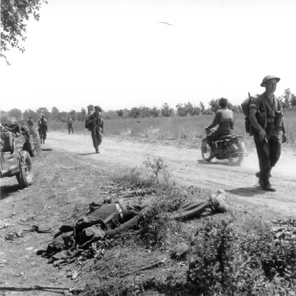 <p>Soldati canadesi avanzano verso il Melfa; sul ciglio della strada il corpo di un soldato<br /> tedesco (Maggio 1944).</p>