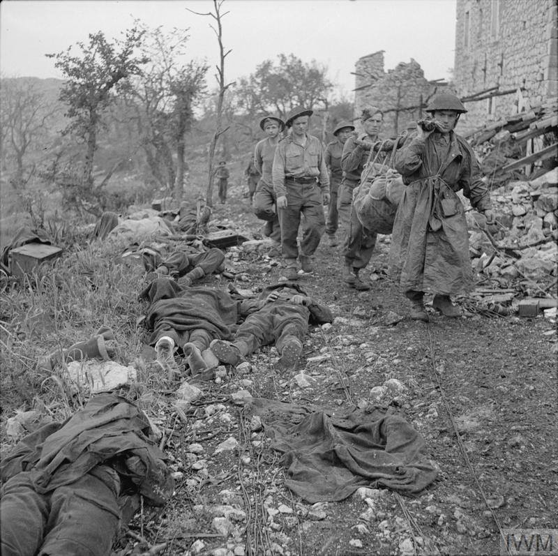 <p>Maggio 1944. I corpi dei caduti polacchi raccolti presso la "Casa del Dottore" in attesa di sepoltura.</p><p class='eng'>Soldiers of the 2nd Brigade, 3rd Carpathian Rifles Division (2nd Polish Corps) bringing their dead comrades from the battlefield after the last battle of Monte Cassino, 19 May 1944. They are passing by the 3rd Division's Advanced Dressing Station, so called 'Domek Doktora' - 'Doctor's House'. © IWM NA 15138</p>