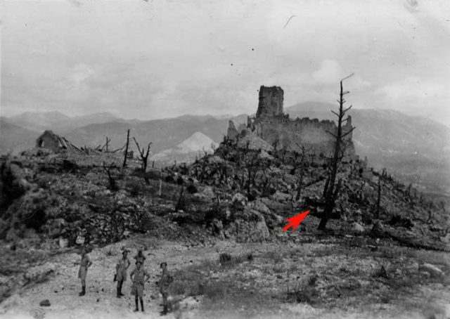 <p>Immagine di presunta fonte polacca che ritrae alcuni soldati sul tornante di quota 165. La freccia rossa indica il relitto dello Stug.</p>