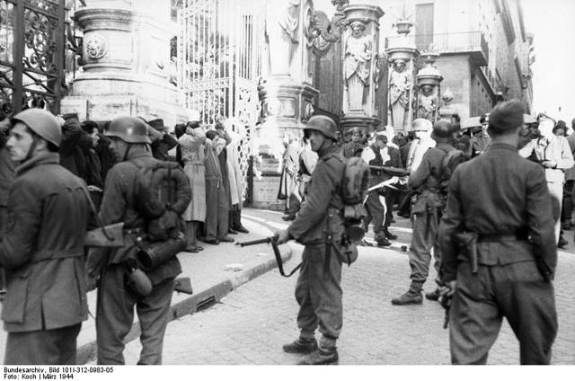 <p>Retata di fronte al Palazzo Barberini a Roma, da parte di truppe naziste e della RSI, dopo l'attacco partigiano in Via Rasella contro una pattuglia del Battaglione "Bozen", il 23 marzo 1944.</p><p class='eng'>March 1944, German policemen of "Bozen" Battalion in Rome.</p><p class='eng'>Bundesarchiv_Bild_101I-312-0983-05,_Rom,_Festnahme_von_Zivilisten<br />Italien, Rom. Festnahme von Zivilisten durch deutsche und italienische Soldaten nach dem Attentat in der Via Rasella auf eine Südtiroler Polizei-Einheit am 23. März 1944 vor dem Palazzo Barberini.</p>