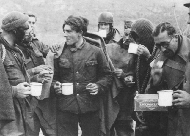 <p>30 dicembre 1943. Alcuni membri del No.9 Commando si ristorano assieme ad uno dei soldati tedeschi catturati nel corso del raid (operazione Partridge) nelle posizioni nemiche sul fiume Garigliano.</p><p class='eng'>Commandos, with tea and blankets grouped around a German prisoner.<br />Taken by Sgt. Mott 30.12.43. © IWM NA 10445<br /><br />----<br />from https://www.facebook.com/karen.sleith<br />My Granda Tommy (paddy) Sleith is 2nd on the right of photo 3453 again wearing a snood drinking from a cup. He is also 1st on the right of photo 3454 with his face dark and wearing a snood.</p>