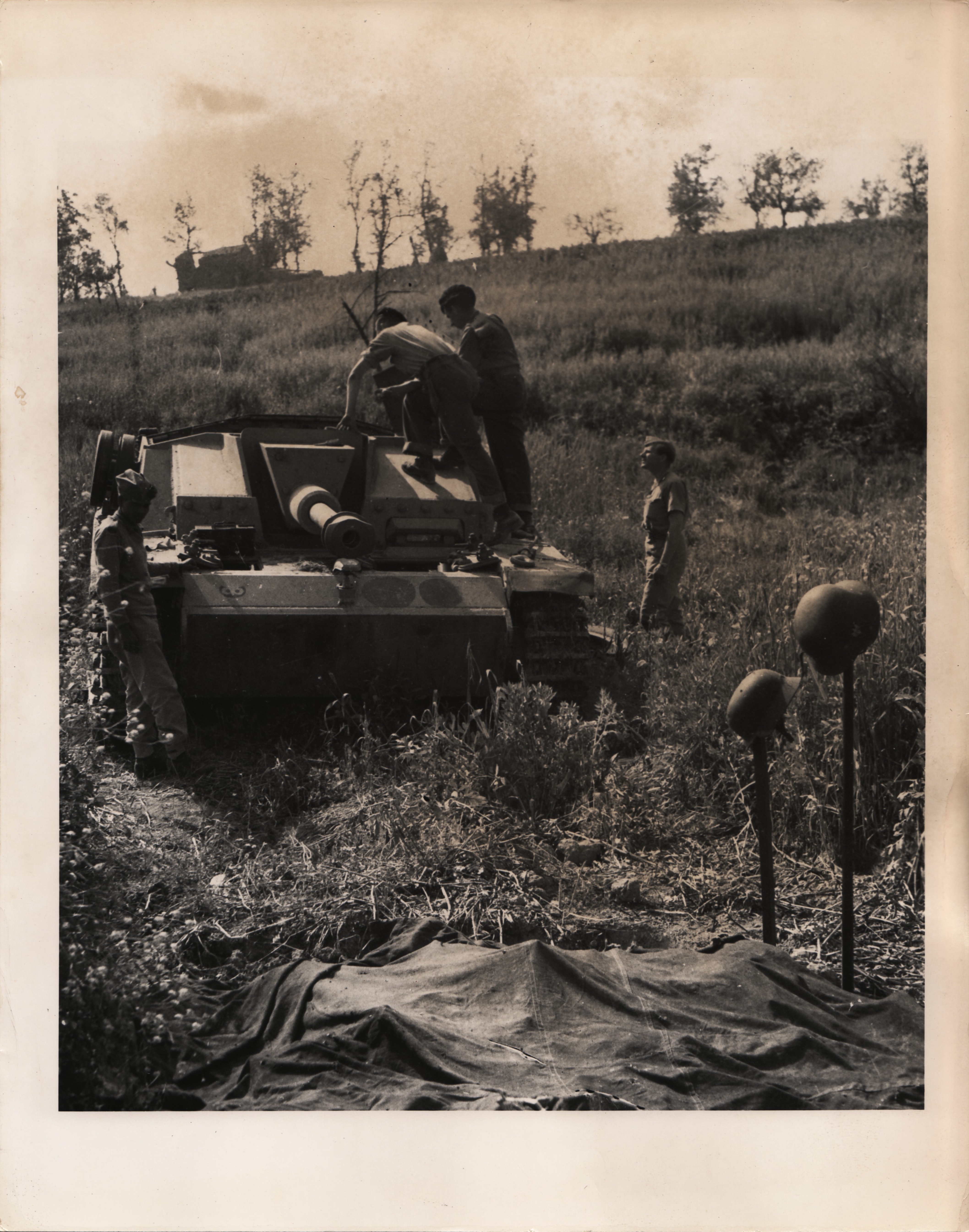 <p>Linea Senger, maggio 1944, campagna di Aquino. Soldati canadesi esaminano uno StuG III. Gli elmetti sui fucili servono a localizzare i corpi di due membri dell’equipaggio pietosamente ricoperti da un telo.<br />Il cannone semovente apparteneva alla SturmGeschutz Brigade 907, come si evince dal simbolo sulla parte frontale sx (per chi vede) del carro.</p><p class='eng'>PIGNATRO (sic!) AREA, ITALY... MAY 18, 1944... CAUGHT BY THE FIRE OF SHERMAN TANKS OF A CANADIAN TANK REGIMENT AFTER THEIR DRIVE ACROSS THE GARI RIVER, THIS GERMAN TANK WAS INCAPACITATED AND IT'S CREW WHEN THEY TRIED TO ESCAPE KILLED. THE CREW LIES UNDER THE COVERS IN THE FOREGROUND M<RKED BY THE HELMETS. CANADIAN ARMY FILM UNIT PHOTO THRU PWB-OWI... SERVICED "E" AND NAPLES LIST AND R ..........<br />APPROVED BY APPROPRIATE MILITARY AUTHORITY........ PHOTO NO. 877</p>