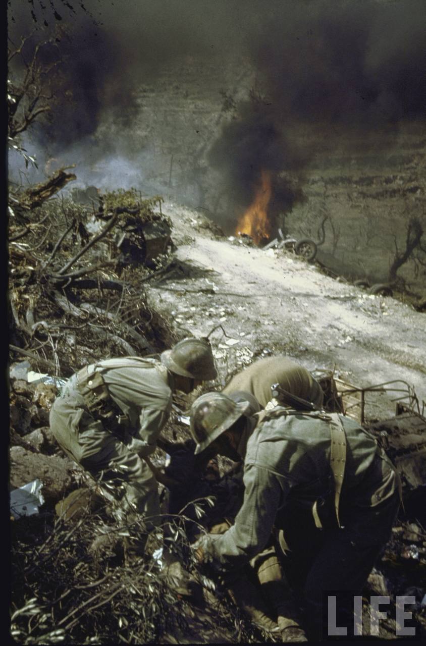 <p>Esperia, 17 maggio 1944. Alcuni automezzi della 3a divisione di fanteria algerina vengono colpiti dall’artiglieria tedesca, mentre transitano di fianco ai resti della colonna tedesca.<br />Il cappellano militare, padre Baudouin, presta i primi soccorsi ai feriti. Photographer: George Silk.</p>