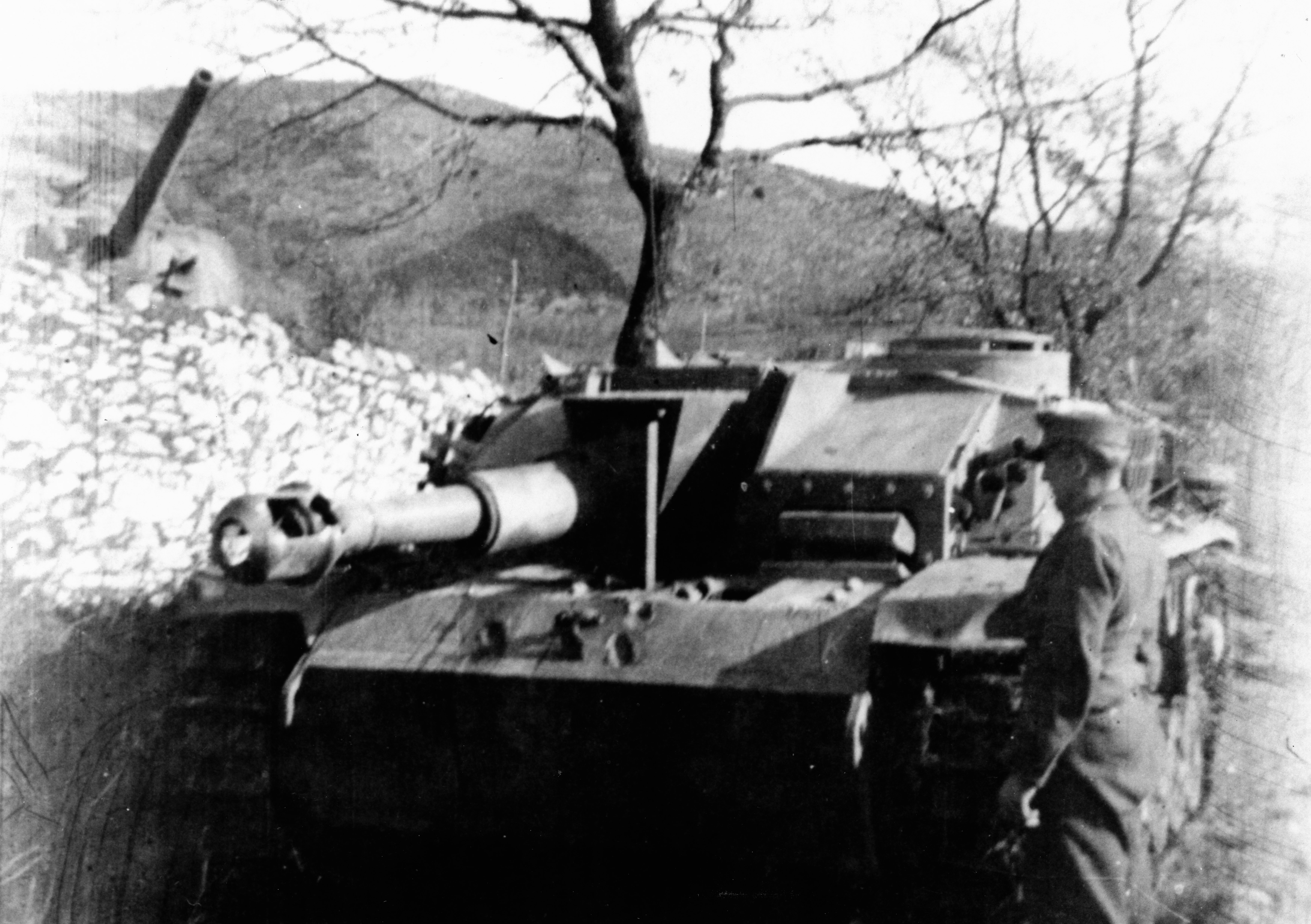 <p class='eng'>The damaged StuH III from 3. Batterie, which I believe was south of Cassino.<br />Behind the wall can be seen one of the Shermans captured by StuG-Abt 242 during the second battle and who was moved south of Cassino and assigned to their Sturmhaubitze platoon.</p>